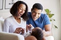 Happy African American  young adult parents playing with their three month old baby son, lying on his motherÃ¯Â¿Â½s knee, selective f Royalty Free Stock Photo